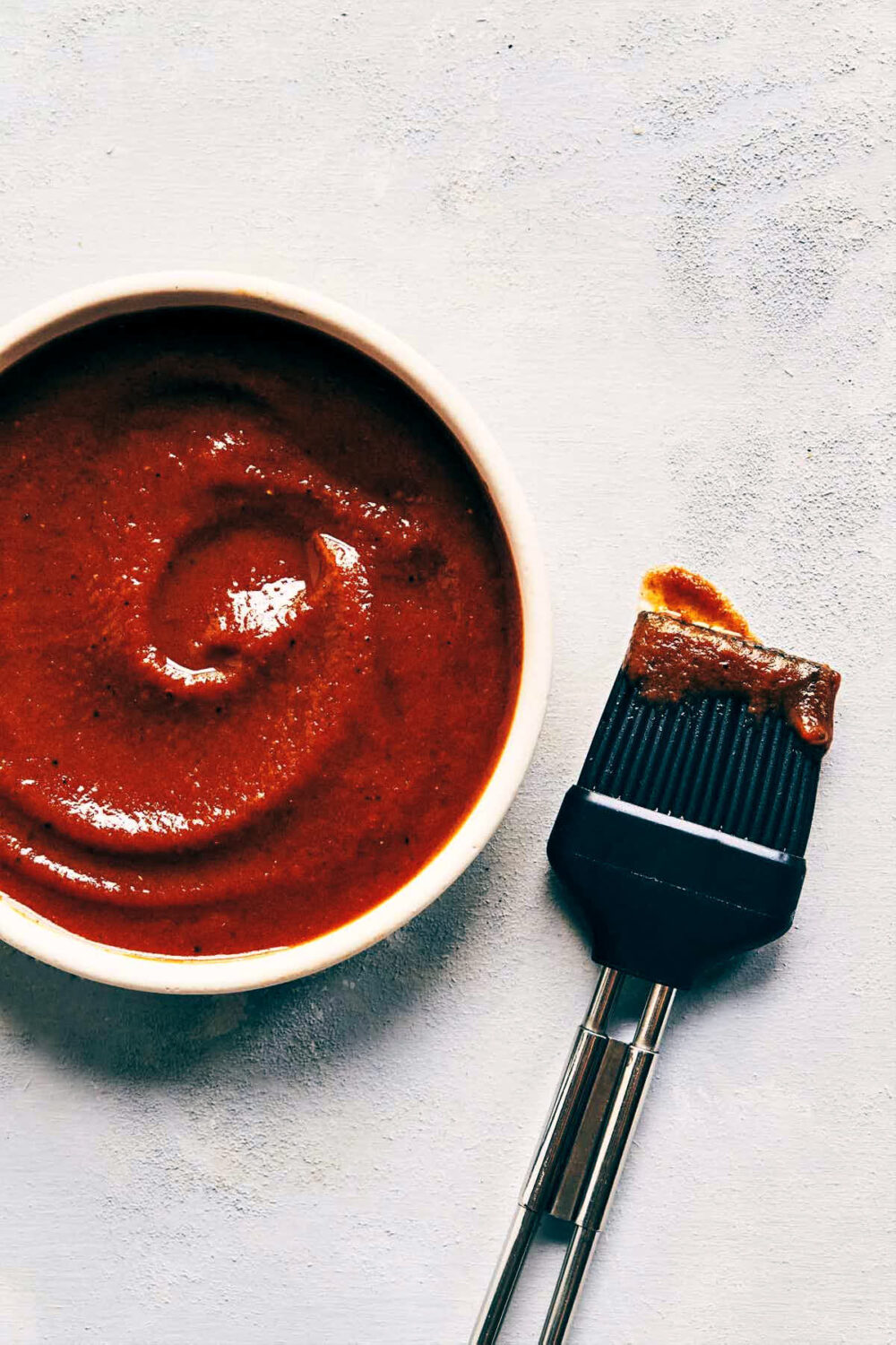 Homemade barbeque sauce on a surface with a brush