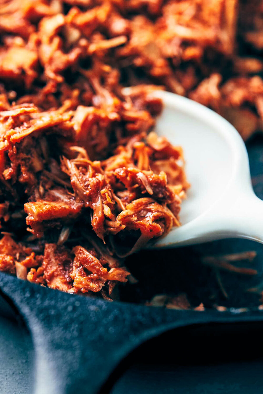 Vegan pulled pork being cooked down with homemade barbecue sauce in a cast iron pan