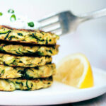 Digging into zucchini fritters topped with dill yogurt sauce