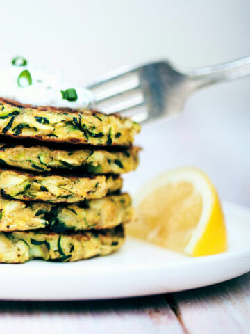 Digging into zucchini fritters topped with dill yogurt sauce