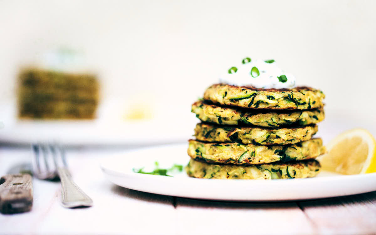 Side view of zucchini fritters on a white plate