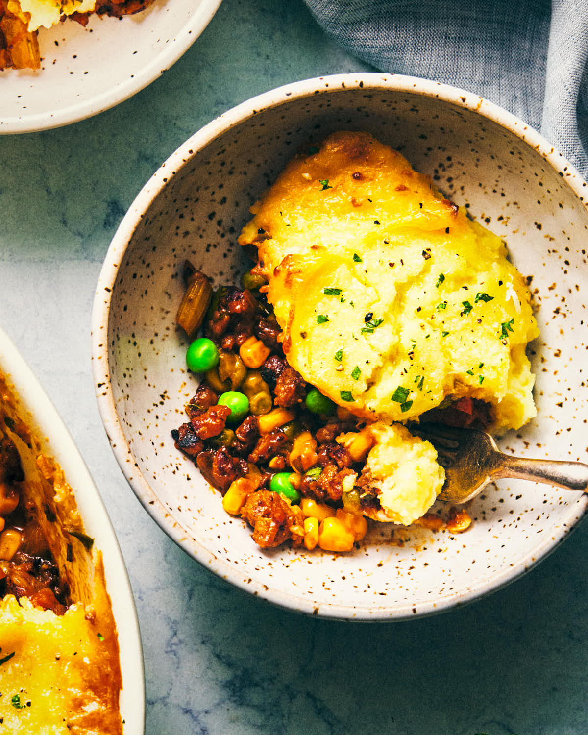 Close up on bowl of vegetarian shepherds pie being eaten with fork