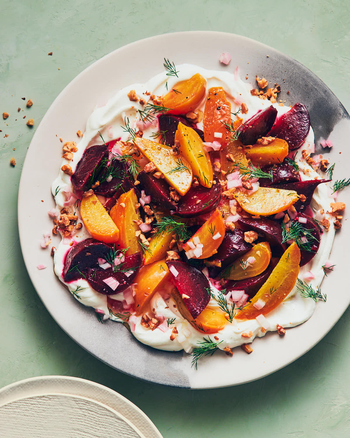 Labneh topped with roasted beets and dill on a light green table