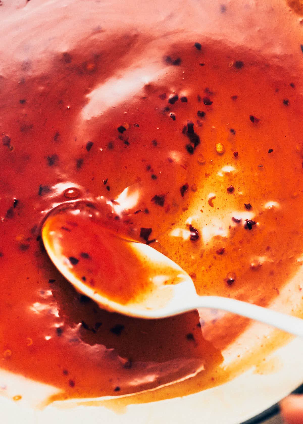 White spoon swirling sweet chili sauce