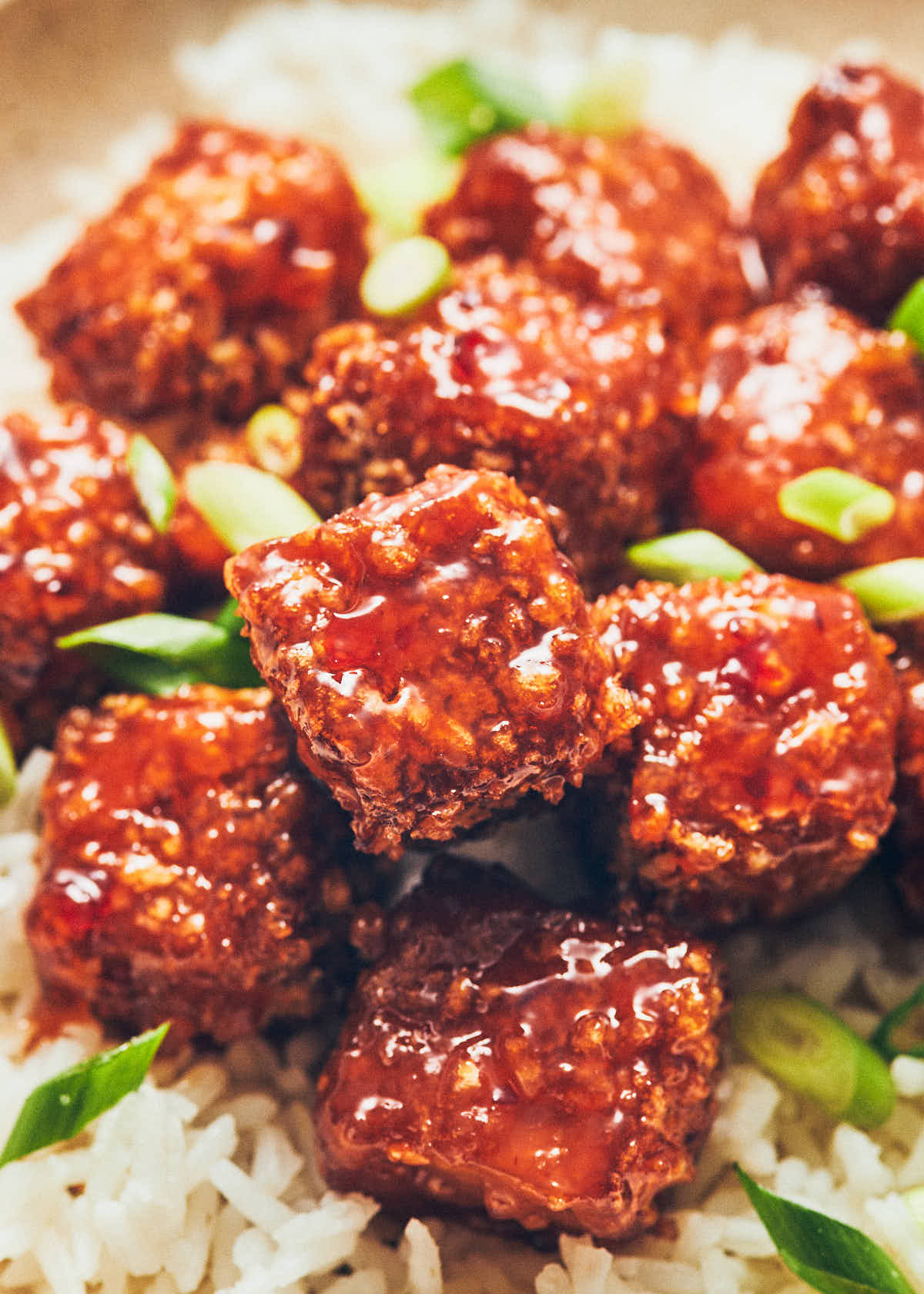 Crispy cubes of air fryer tofu coated in sweet chili sauce, with white rice and scallions