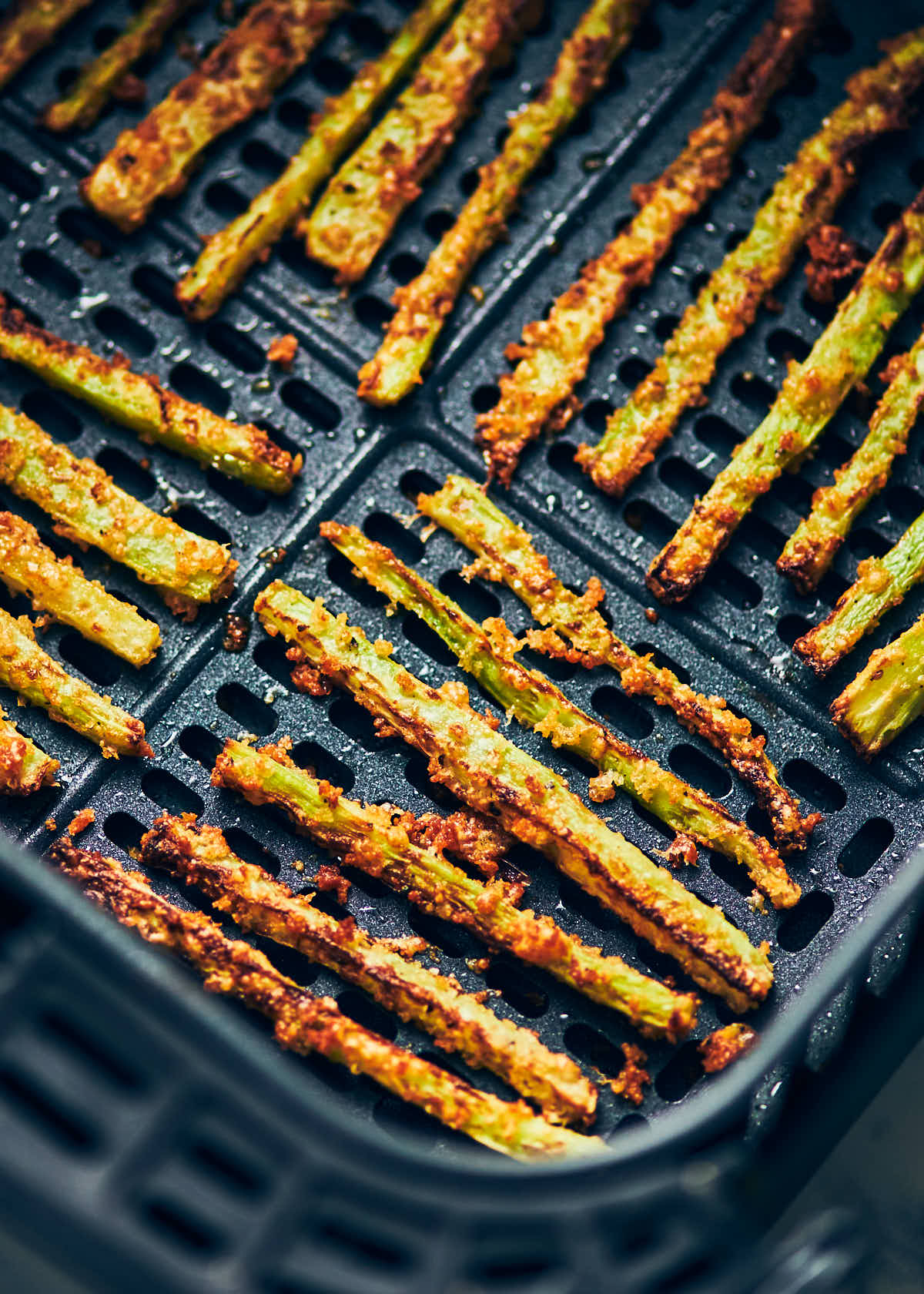 Rows of broccoli fries in air fryer directly after cooking