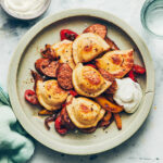 Plate of pierogies with plant based sausage and sour cream