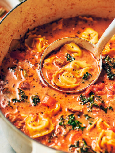 A ladle scooping out Creamy Vegetarian Tortellini Soup out of the pot for serving.