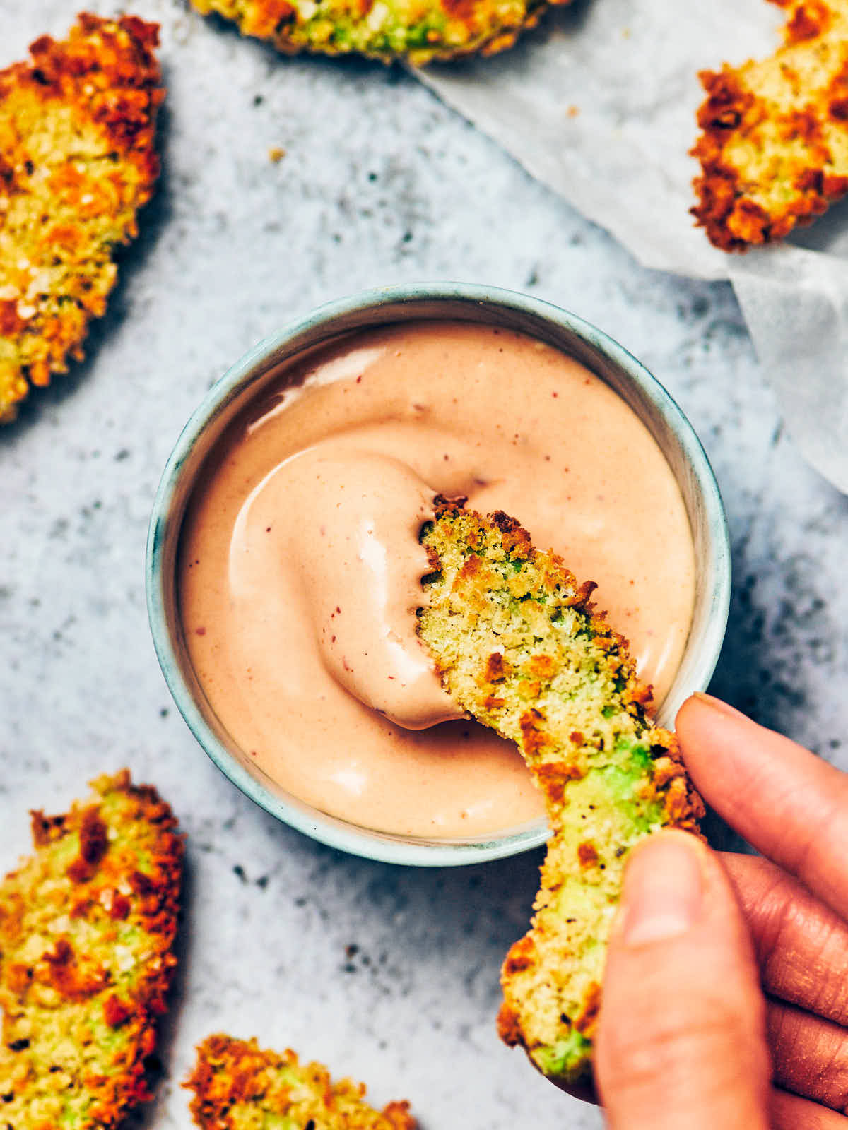 A crispy avocado fry being dipped into vegan chipotle mayo