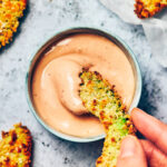 Crispy panko crusted vegan air fried avocado being dipped in chipotle mayo.