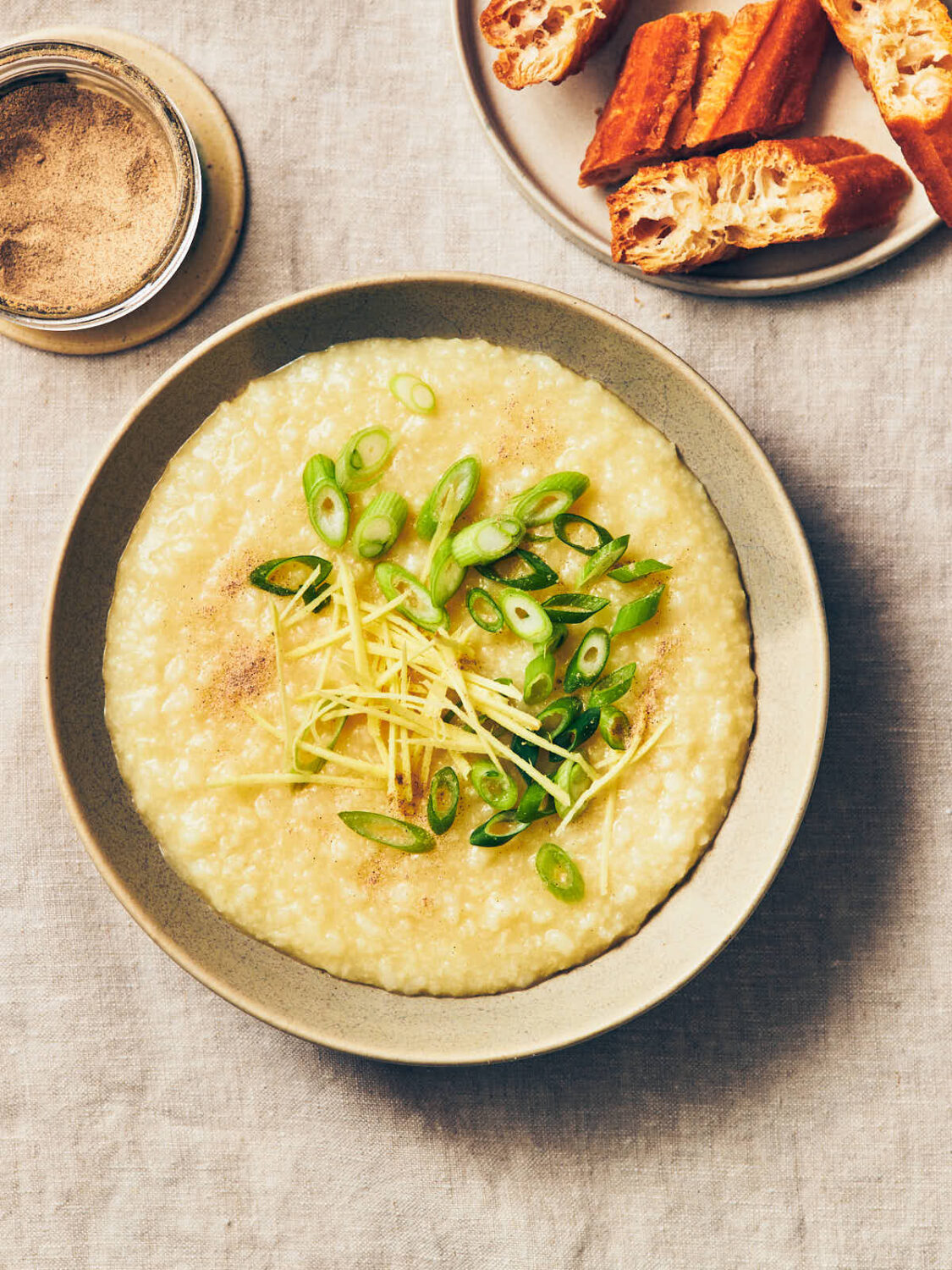 A bowl of vegan congee topped with scallions (green onions), fresh ginger, and white pepper