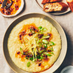 A bowl of vegan congee (rice porrige), topped with homemade chili garlic oil, ginger, and scallions