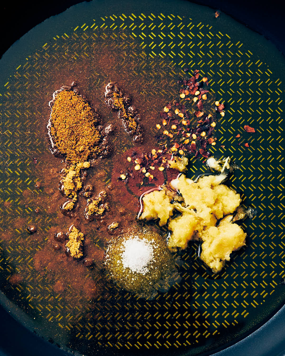 Spices, salt, garlic, and red pepper flakes in a skillet pan with olive oil for halloumi couscous salad.