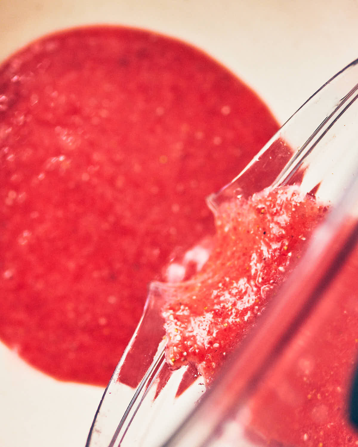 Smooth strawberry puree being poured from blender for strawberry shortcake in a jar.