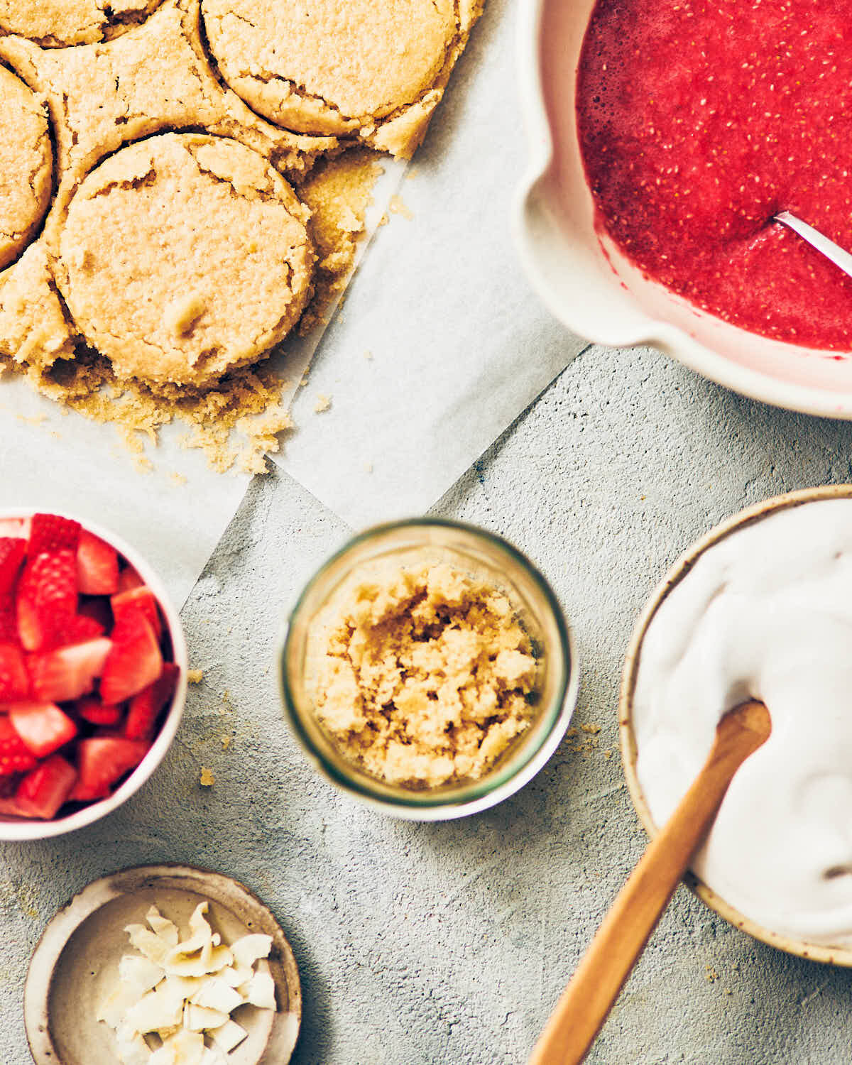 Components for vegan strawberry shortcake trifle: gluten free cake, fresh strawberries, strawberry jam, and whipped cream.