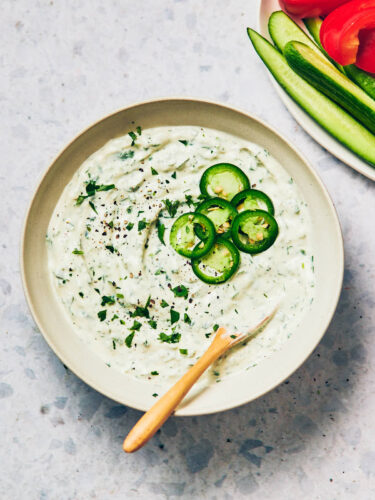 Creamy Jalapeno Ranch Dip with Greek Yogurt in a bowl topped with sliced jalapenos.