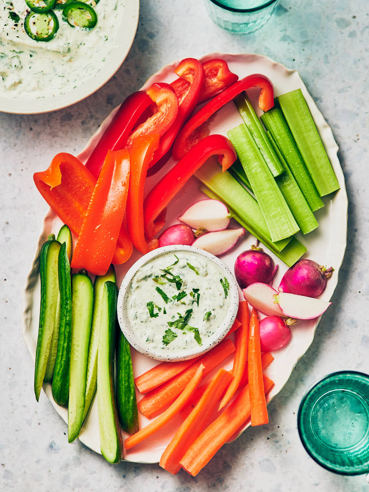 A bowl of creamy Jalapeno Ranch Dip with Greek Yogurt on a platter with fresh veggies.