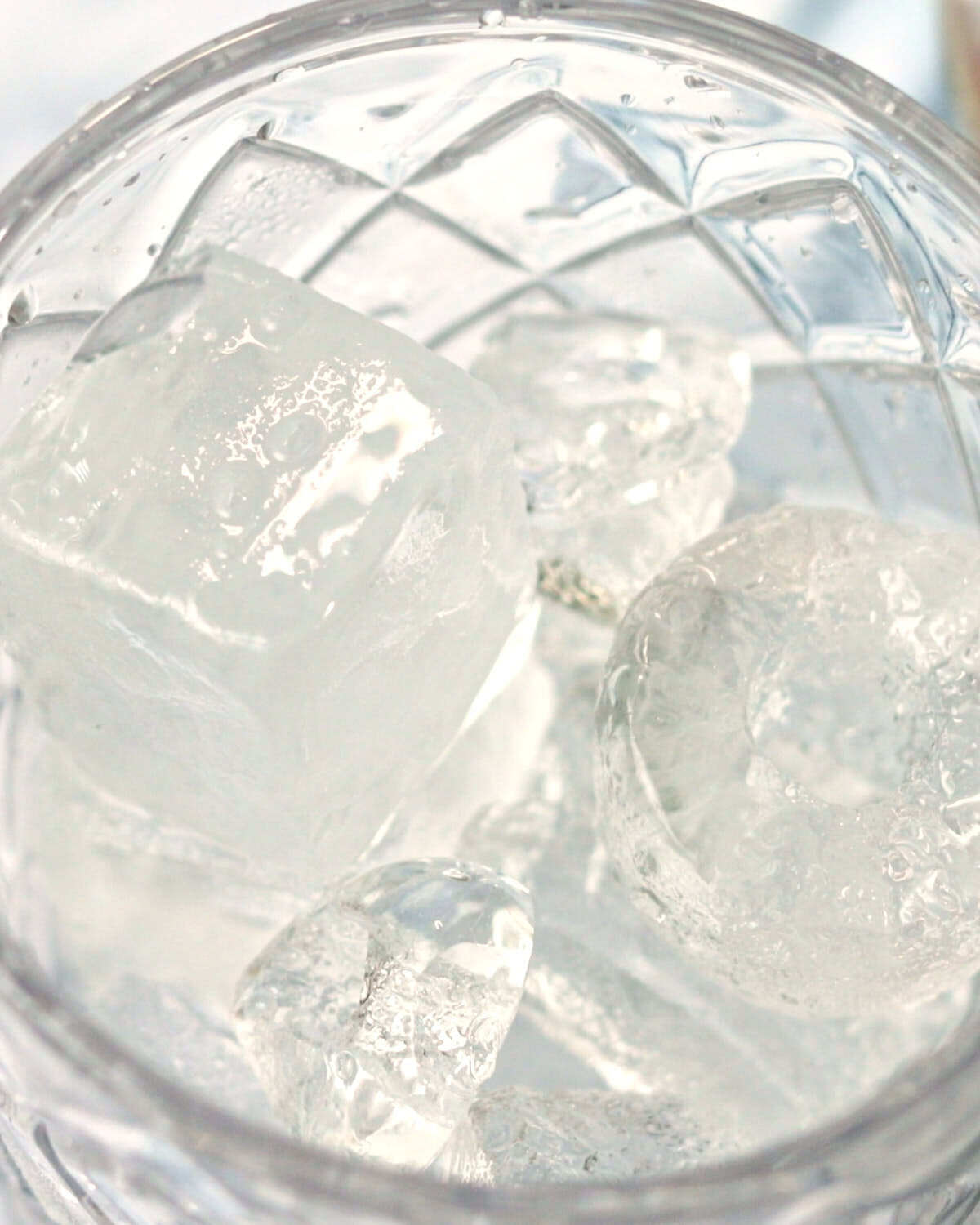 A glass cocktail shaker filled with ice for Spicy Pineapple Margaritas.
