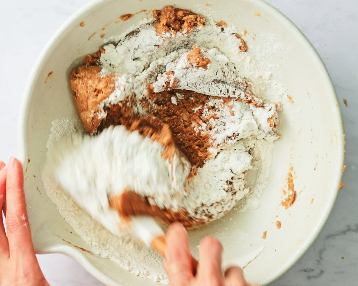 Stirring flour into Vegan Oat Chocolate Chip Cookies batter.