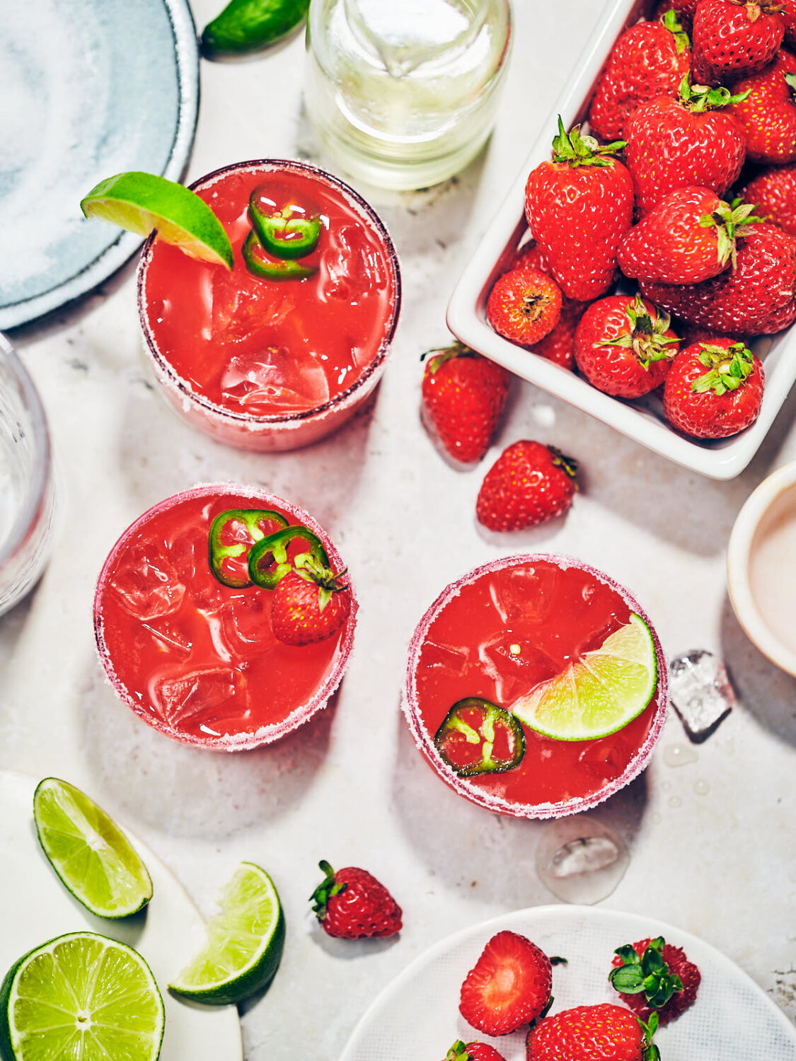 Easy Strawberry Jalapeno Margaritas in glasses on a table with strawberries and lime.