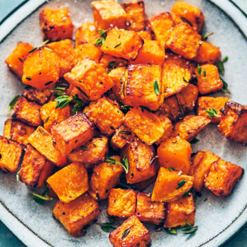 Air fryer butternut squash with thyme on blue plate.