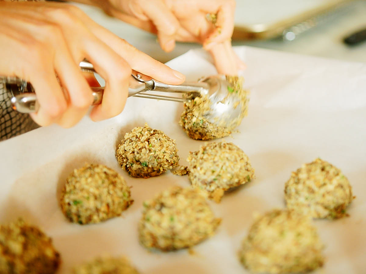 Scooping the veggie meatballs on a parchment lined baking sheet.