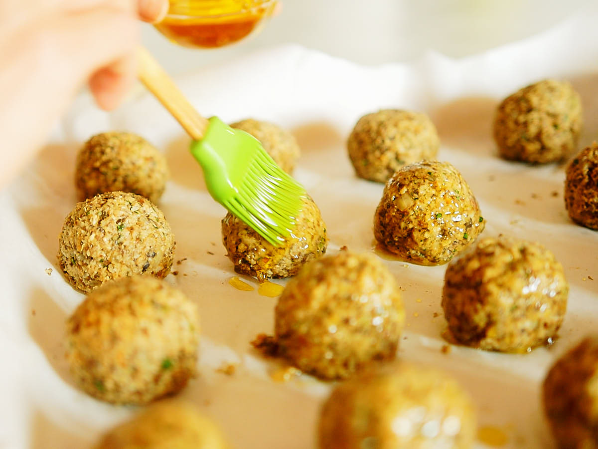Brushing veggie meatballs with olive oil and a silicon pastry brush.