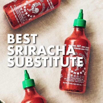 Bottles of Sriracha sauce with green lid on linen tablecloth.