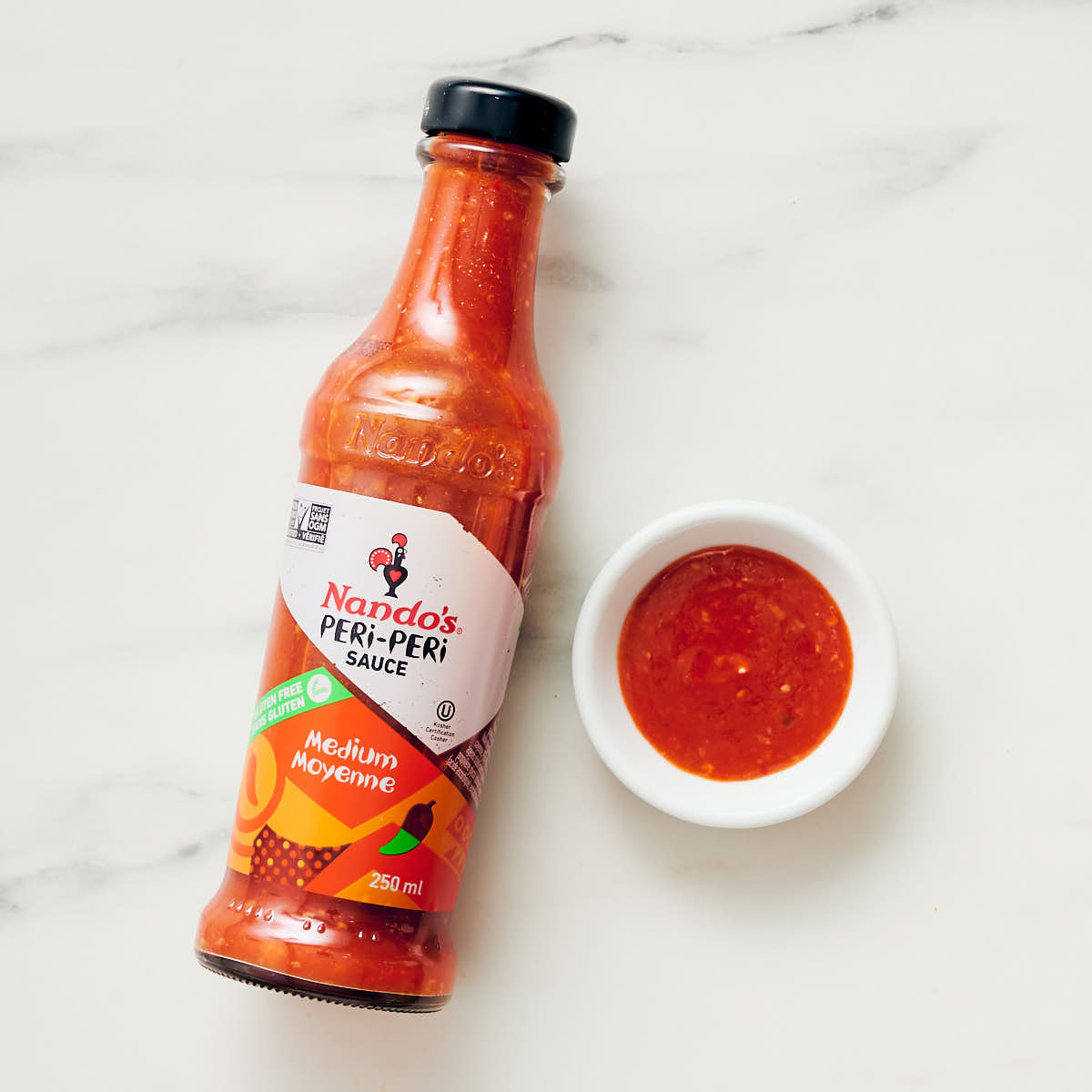 Nando's Peri Peri Sauce in a bottle and hot sauce in a small bowl.