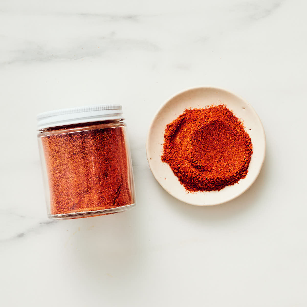 Cayenne in a spice jar and in a small dish on a kitchen counter.