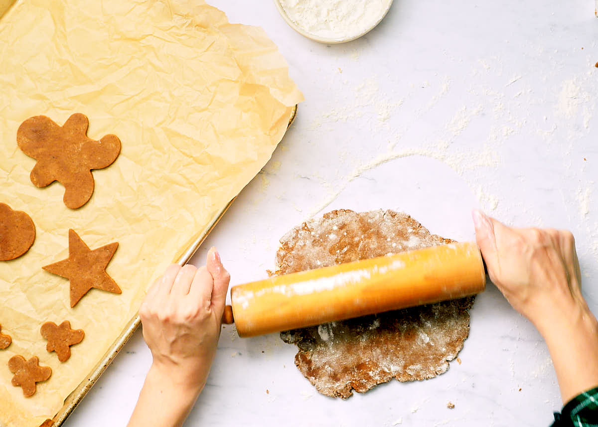 Rolling out gingerbread dough with a wooden rolling pin.