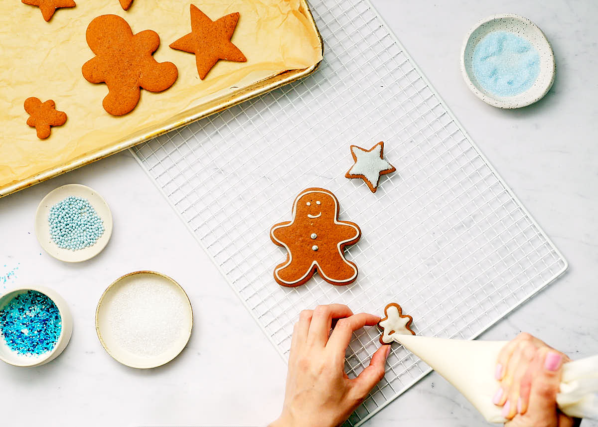 Gingerbread cookies being decorated after being baked.