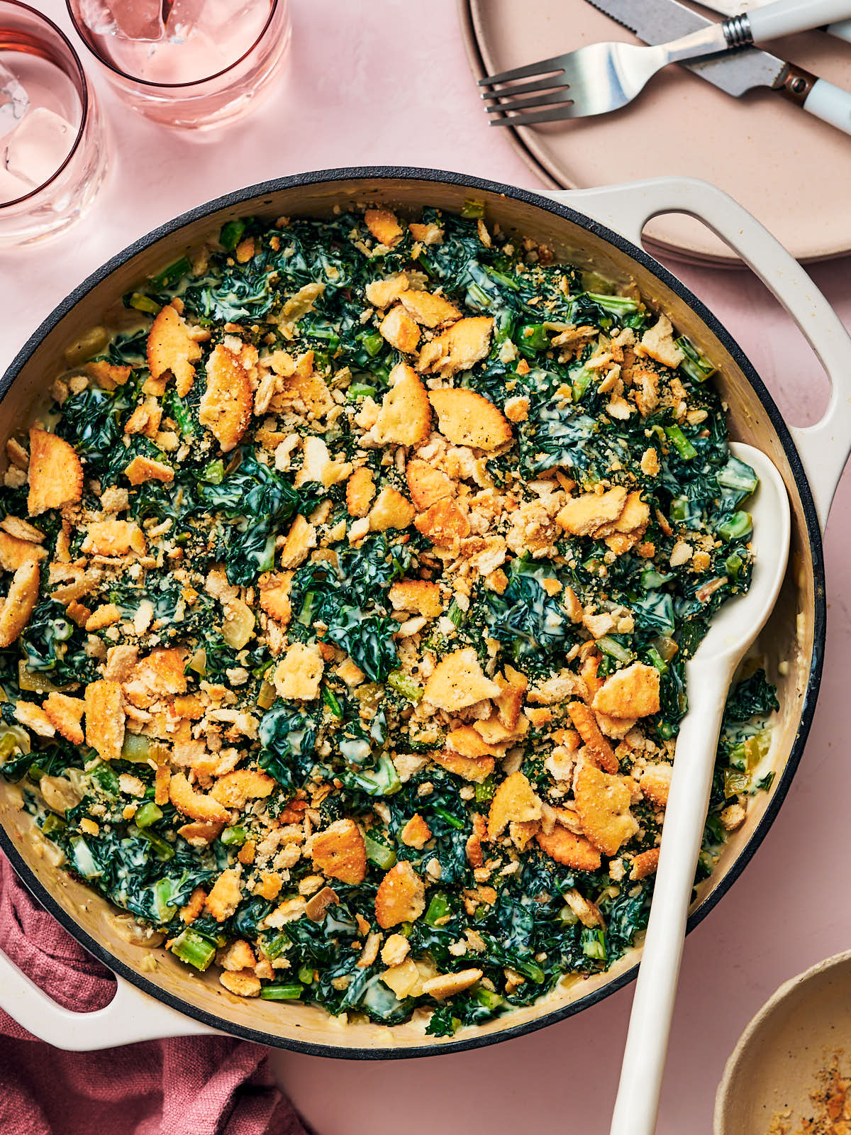 Easy Creamed Kale in a skillet with a serving spoon on a dining table.