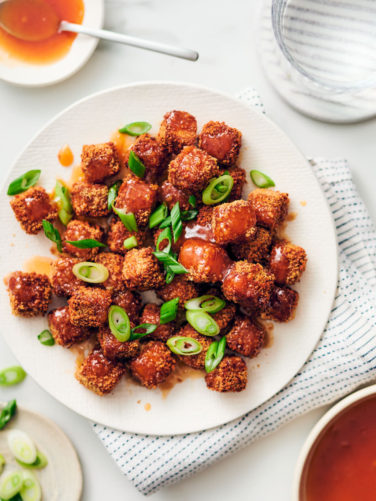 Honey Sriracha Sauce drizzled over crispy breaded air fryer tofu on a plate with green onions.