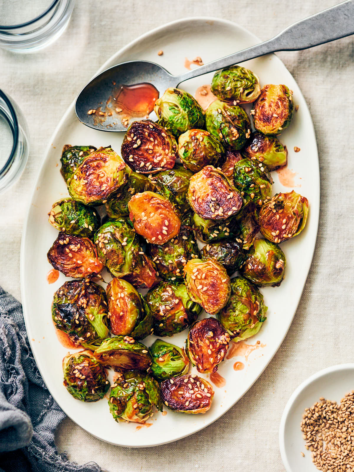 Oven roasted maple sriracha brussels sprouts on a serving platter with spoon.
