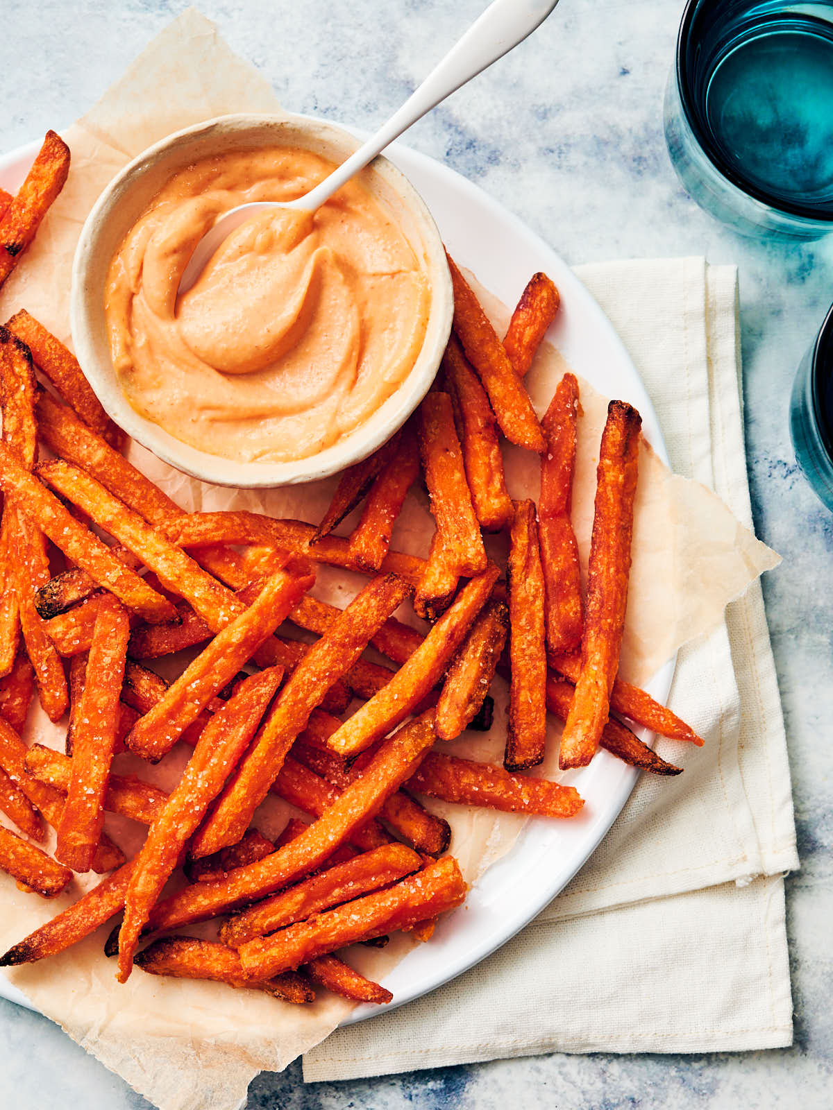Easy Sriracha Aioli in a bowl served with sweet potato fries (yam fries) on a plate.