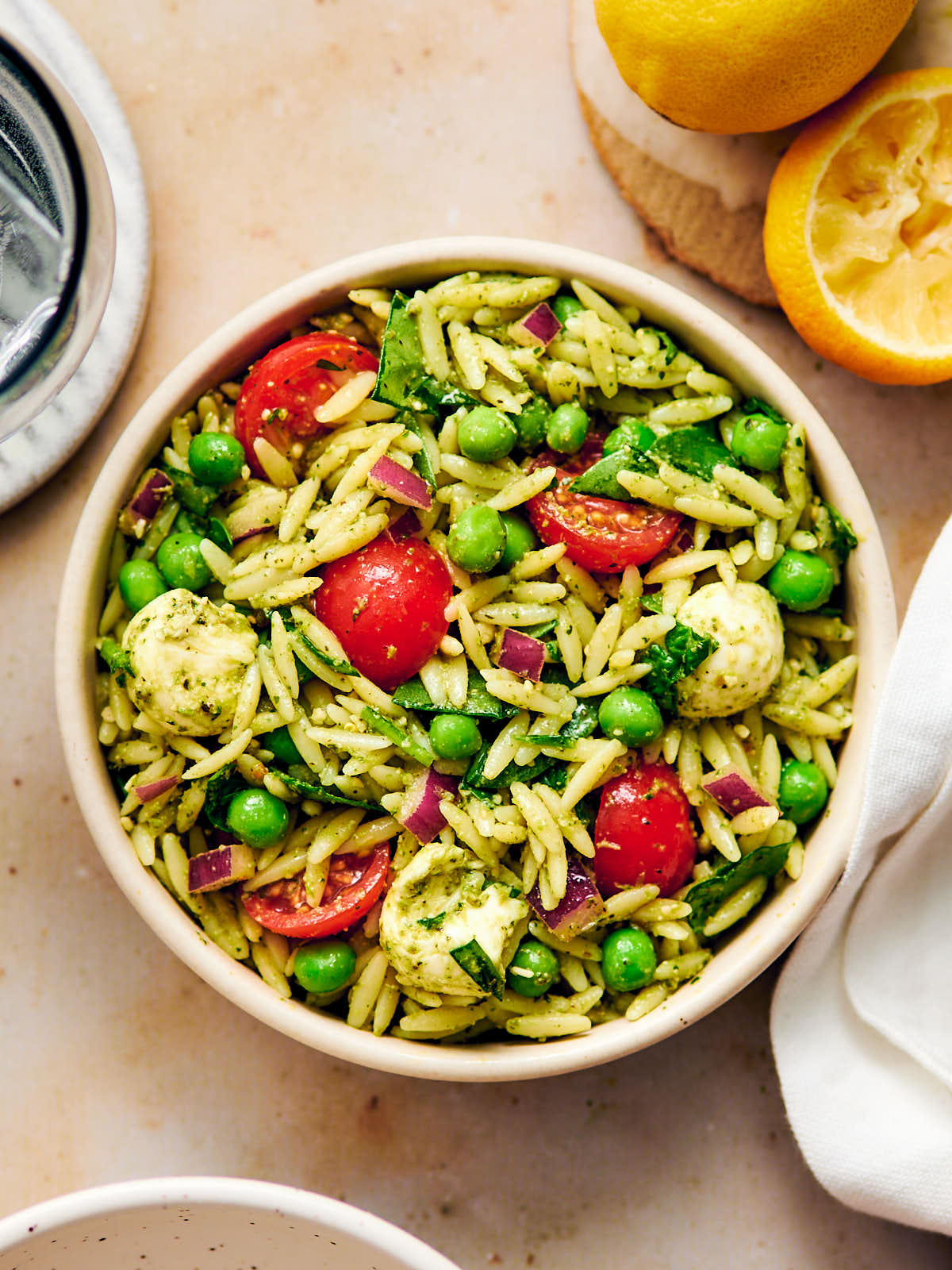 Vegetarian Orzo Pesto Salad with tomatoes, peas, and cheese in a bowl. 