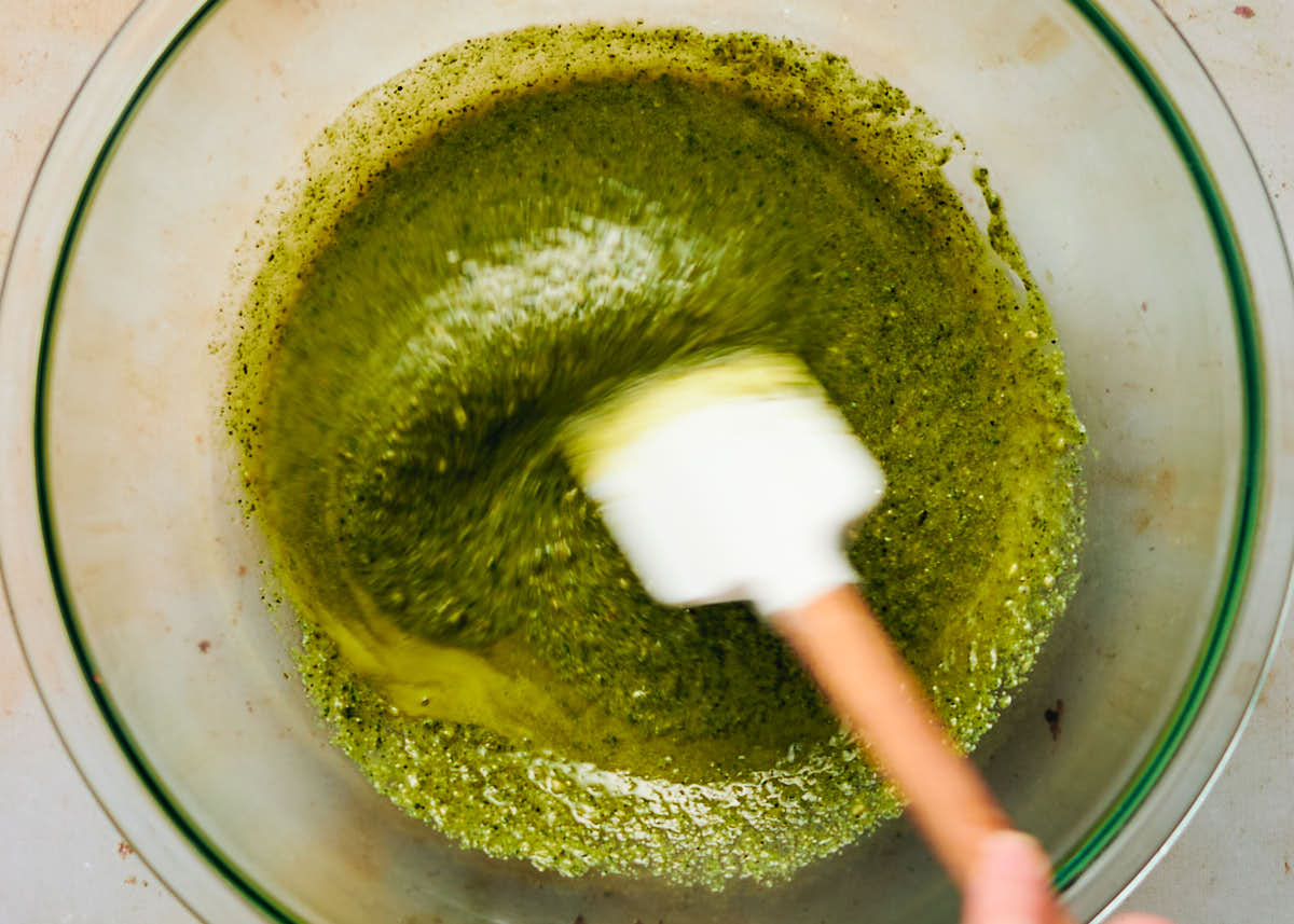 Pesto being mixed in a bowl with lemon juice for orzo pesto salad recipe.