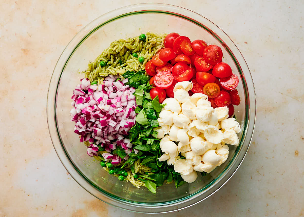 Ingredients for Orzo Pesto Salad in a glass bowl about to be mixed together.