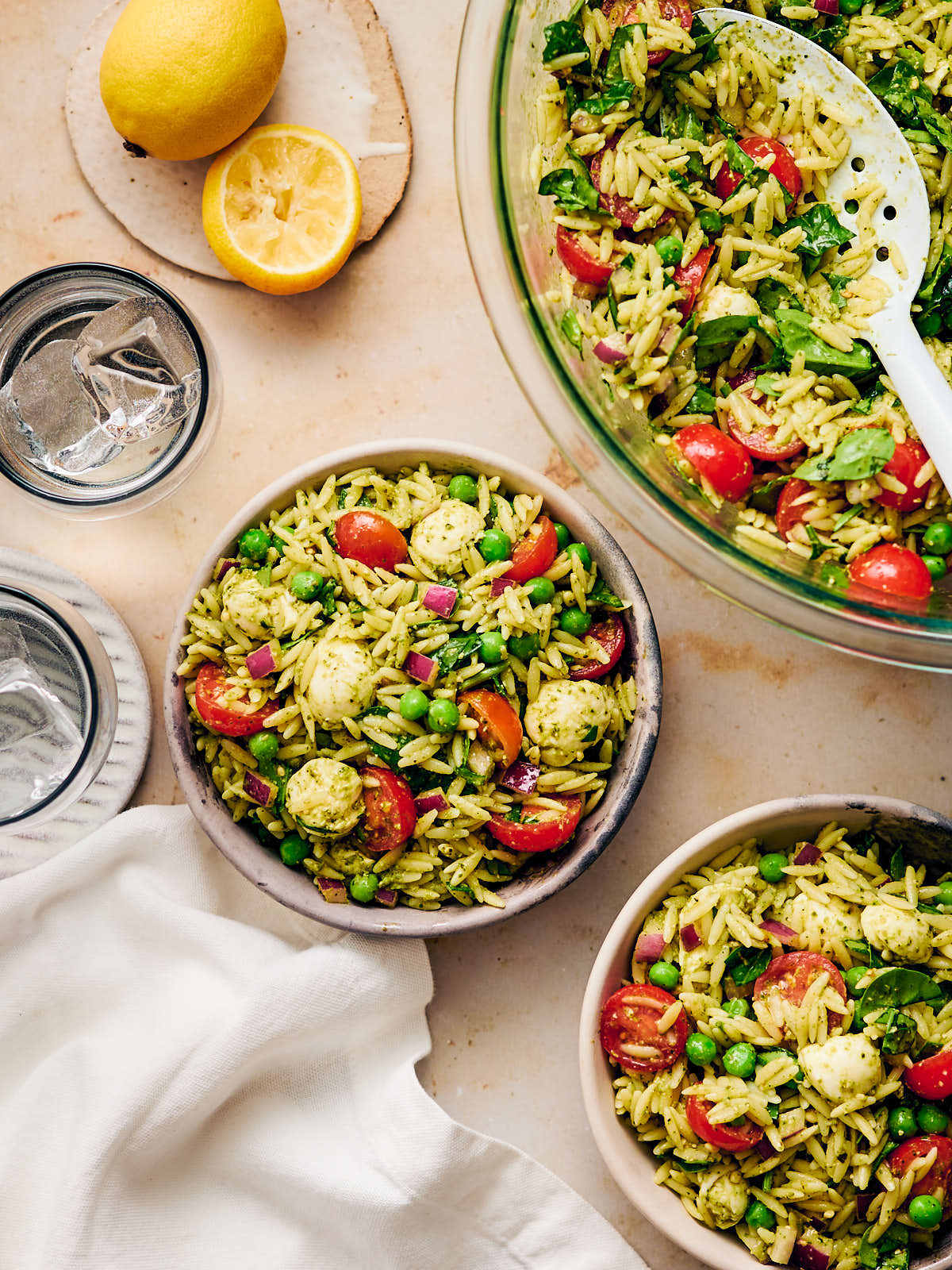 Vegetarian Orzo Pesto Salad being scooped into bowls at the dinner table. 