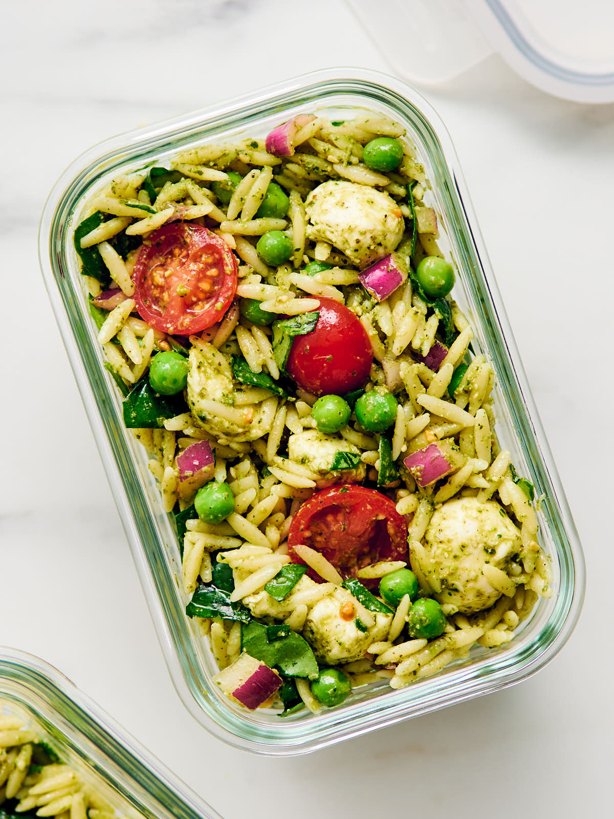 Leftover Orzo Pesto Salad stored in a glass container for meal prep.