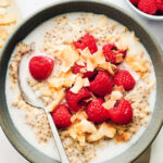 Bowl of Overnight Oats with Coconut Milk, topped with raspberries and coconut.