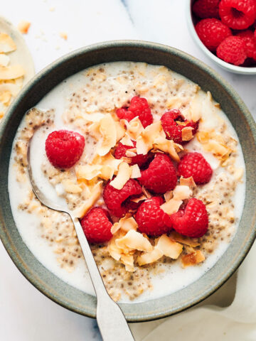 Bowl of Overnight Oats with Coconut Milk, topped with raspberries and coconut.