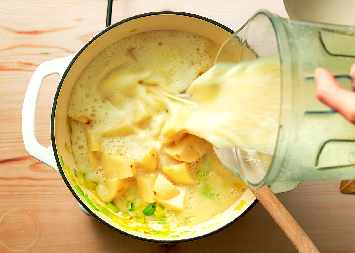 Combining potatoes, cashew cream and seasonings to simmer for potato leek soup.
