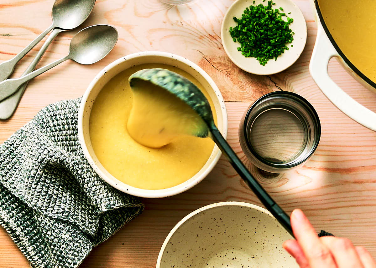 Spooning potato leek soup into bowls to serve.