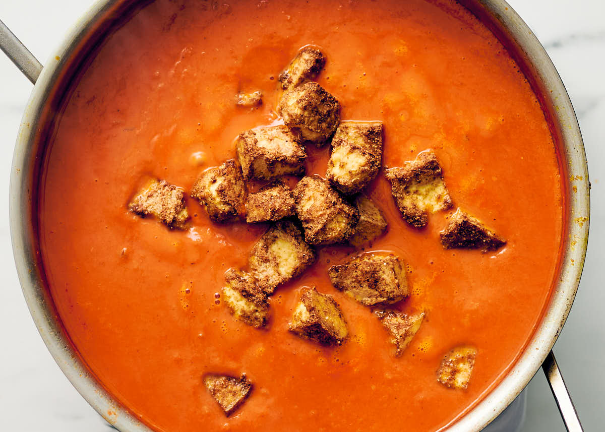 Veggie butter chicken sauce in a pan with oven baked tofu.