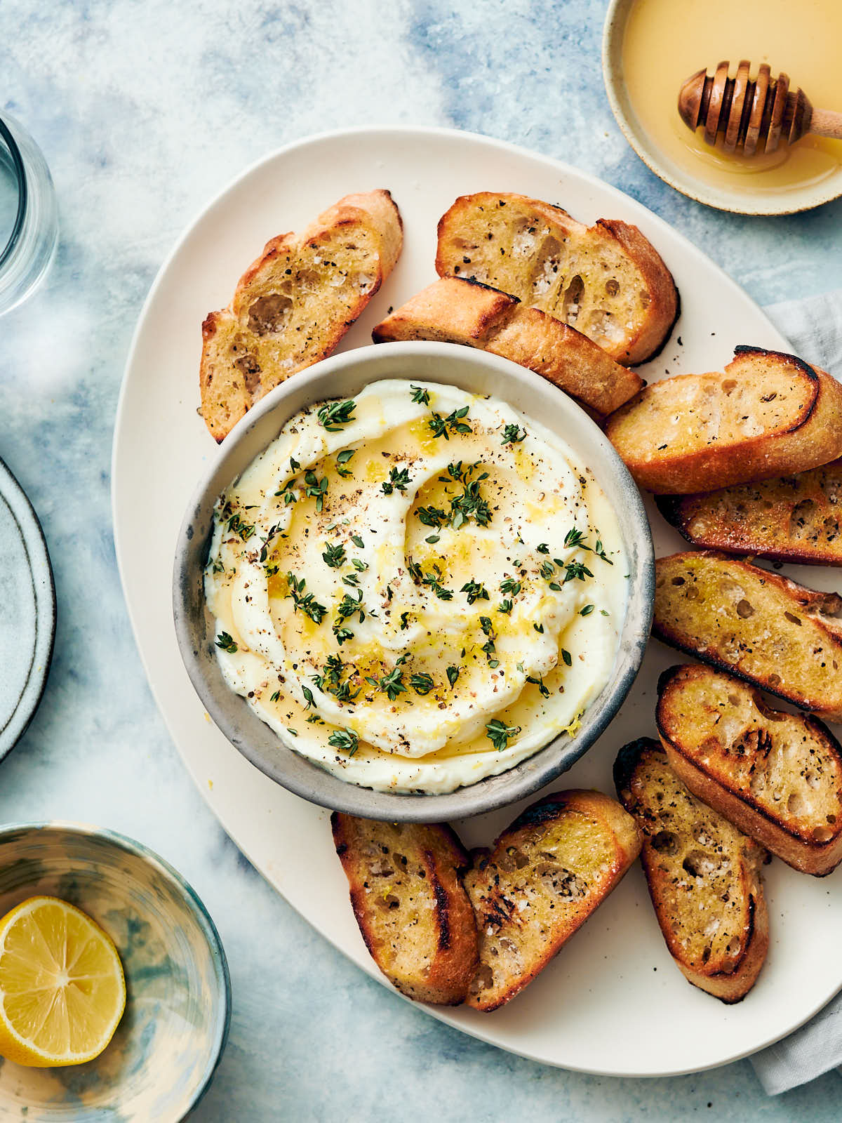 Whipped ricotta dip with honey in a bowl being served with toasted bread.