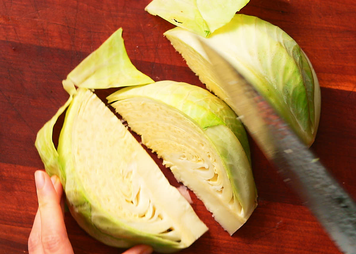 Cutting green cabbage into wedges for air fryer cabbage recipe.