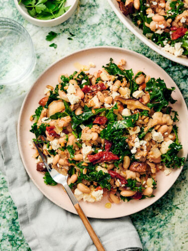 Easy vegetarian farro pilaf with mushrooms and kale on a dinner plate with a fork.