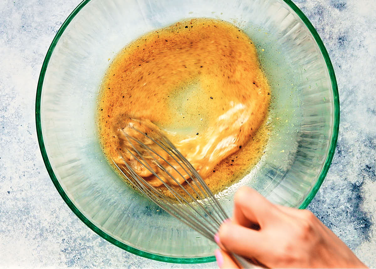 Whisking together dressing in a bowl for easy raw carrot salad. 